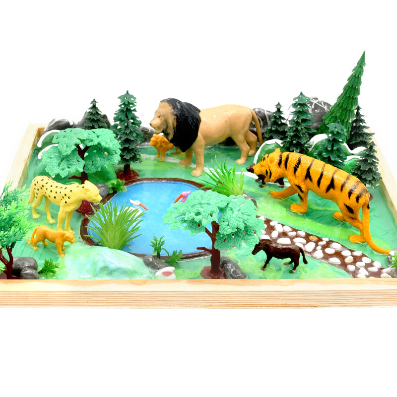 Toy animal figures on a diorama with trees and water