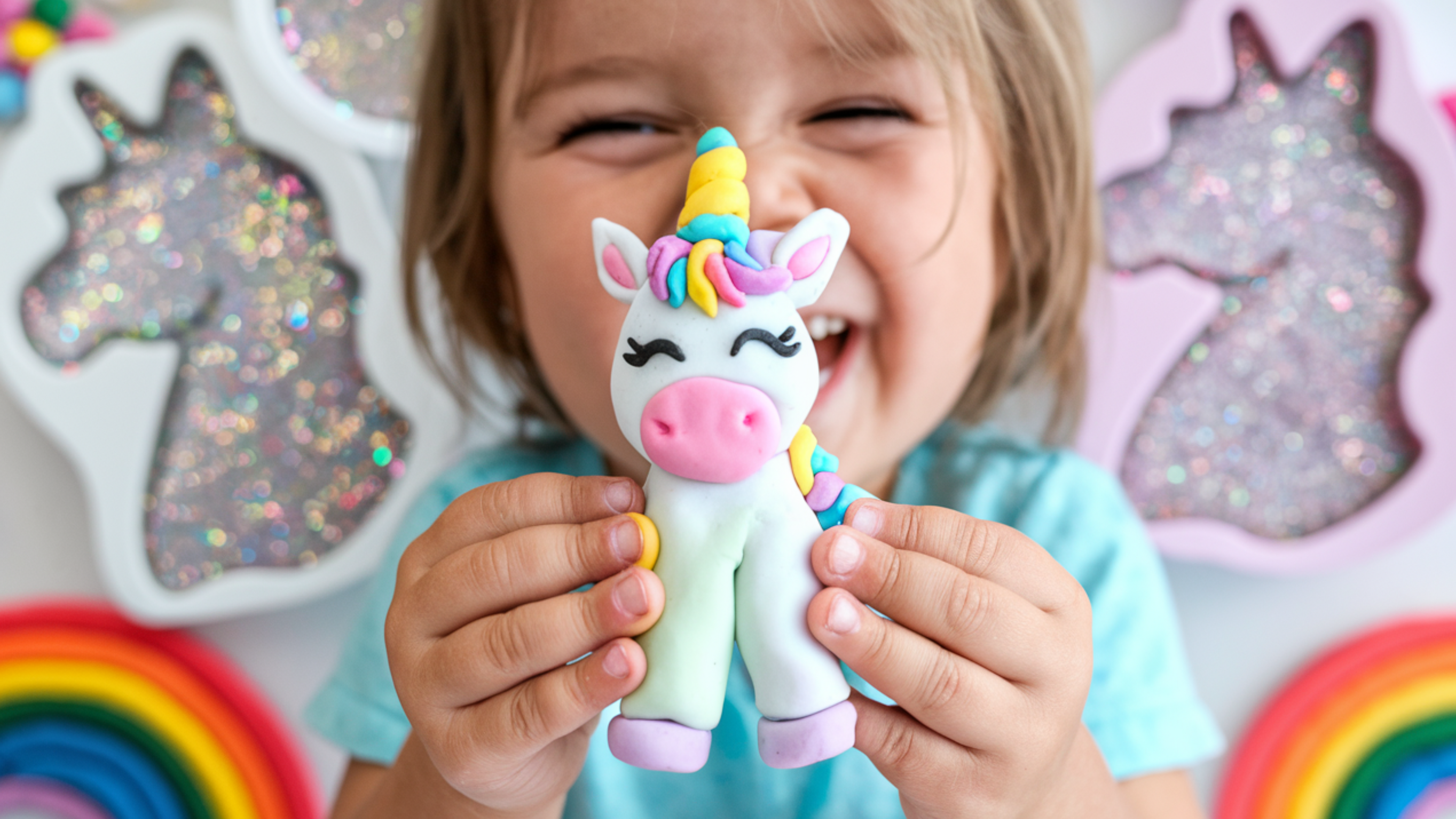 Child holding a unicorn plush toy with colorful decorations in the background