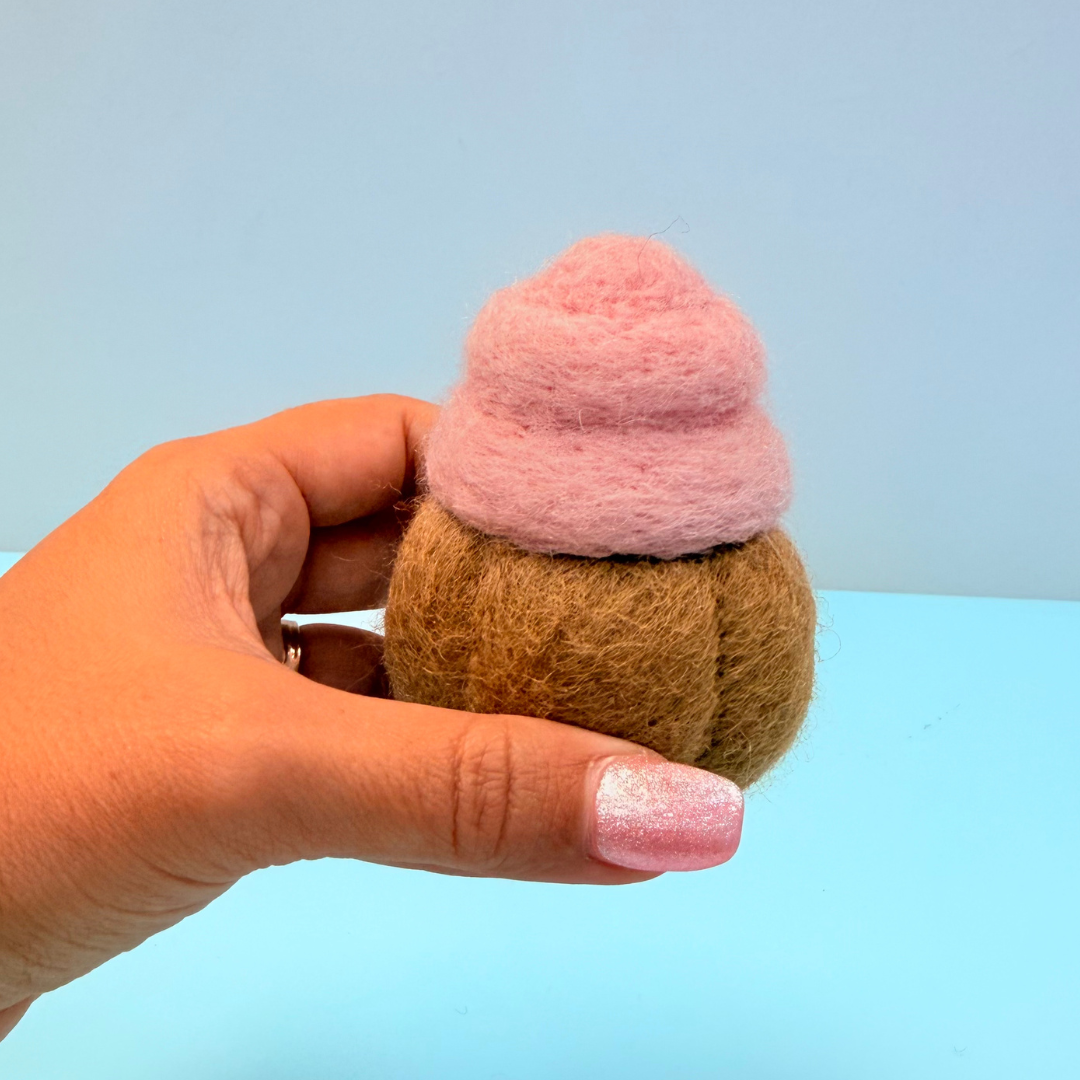 Hand holding a small felted cupcake