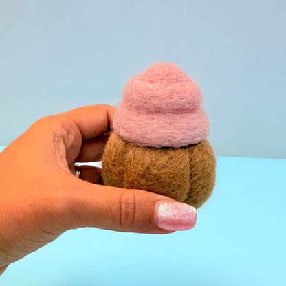 Hand holding a small felted cupcake