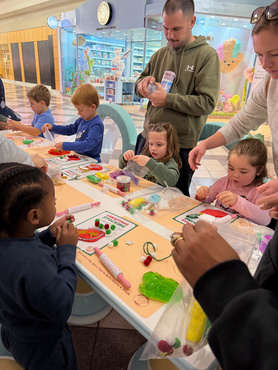 Children and adults gathered around a table with educational materials in a classroom setting.