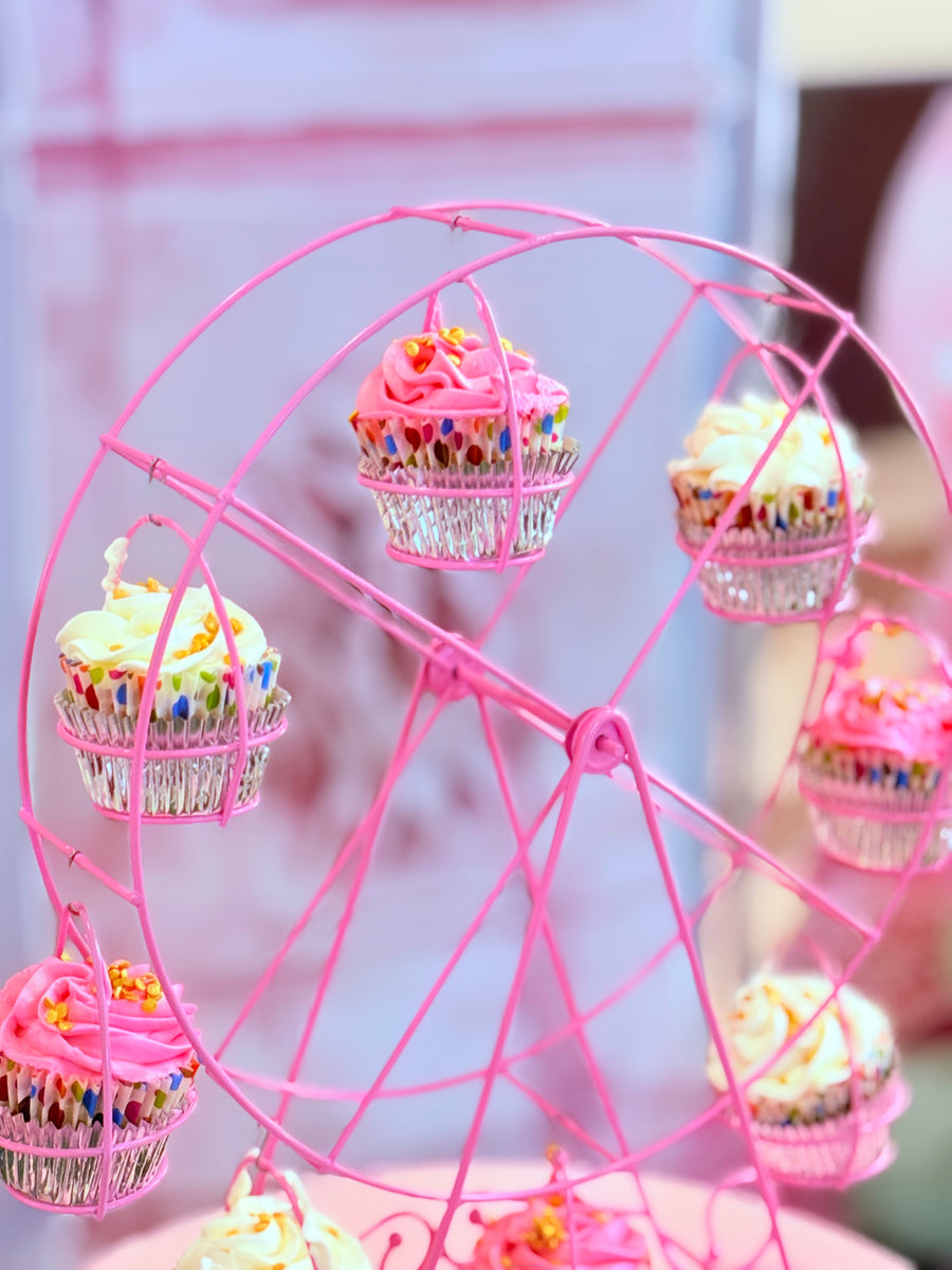 Pink ferris wheel with cupcakes on a blurred background