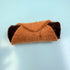 Felted brown and black cat-shaped object on a light blue background
