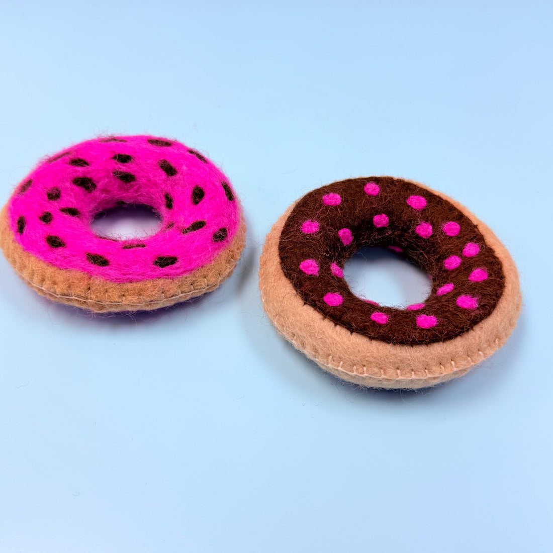 Two felt donut toys with pink and brown colors