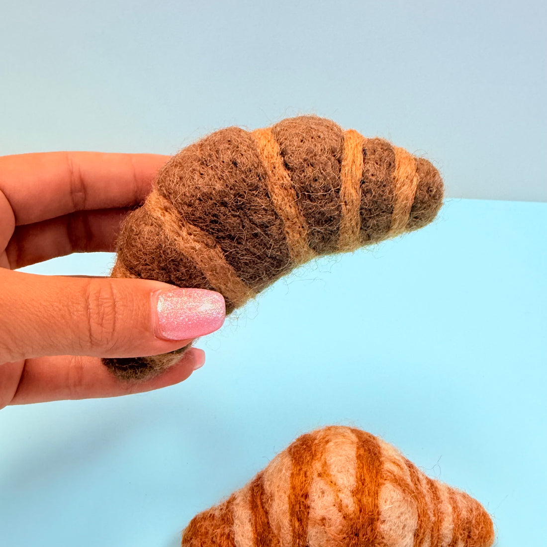 Hand holding a croissant-shaped felted
