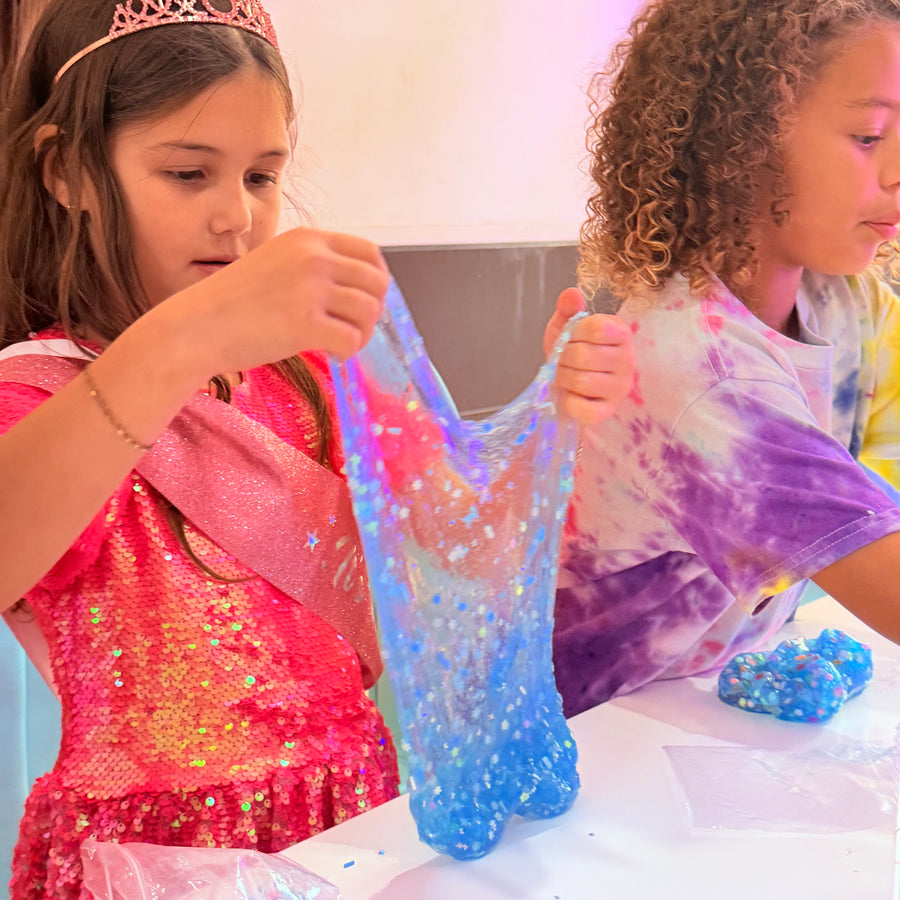 Two children playing with colorful slime at a table.